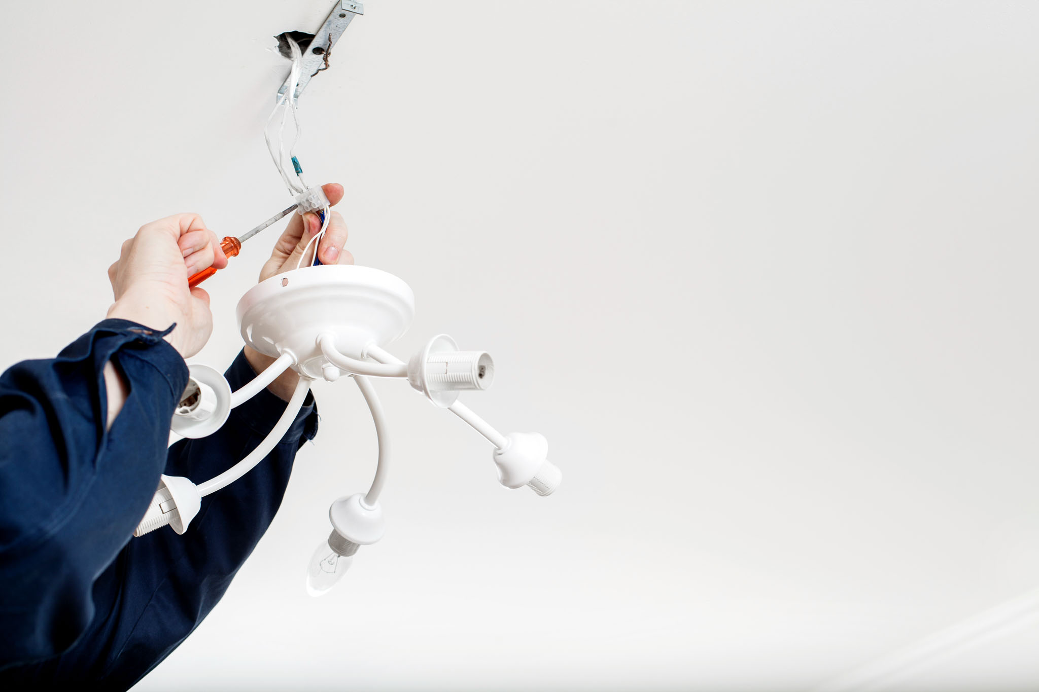 An electrician providing installation services for lighting - get professional services today with WyattWorks Plumbing.
